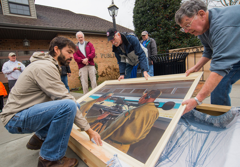 A World War II-era painting by the late Howard Schroeder is packed up Feb. 4 for a journey from its home at Lewes Public Library to a new home at Fort Miles in Cape Henlopen State Park. Carefully wrapping the untitled 1943 painting are (l-r) local artist Abraxas and Fort Miles Historical Association Bunker Busters Pat Bragdon and Richard Ross. In back are Bunker Busters Gary Wray, John Roberts and Steve Tarantolo. Also going to the fort is a portrait of Gen. Nelson Appleton Miles by local artist Mary McCartin Marshall. BY DENY HOWETH